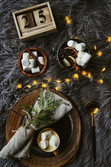 A warm and inviting Christmas flatlay with hot cocoa, marshmallows, and festive decor.