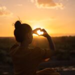 woman sitting while showing heart sign hands