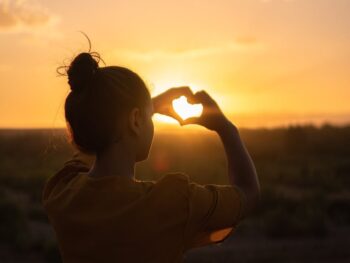 woman sitting while showing heart sign hands