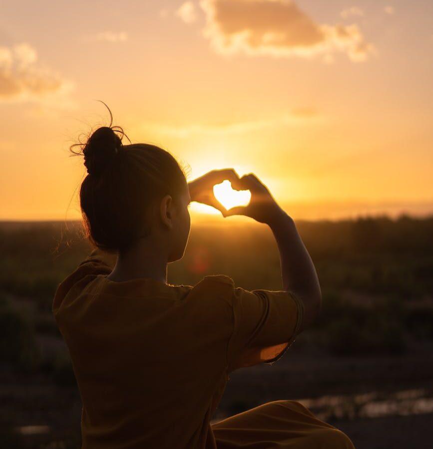 woman sitting while showing heart sign hands